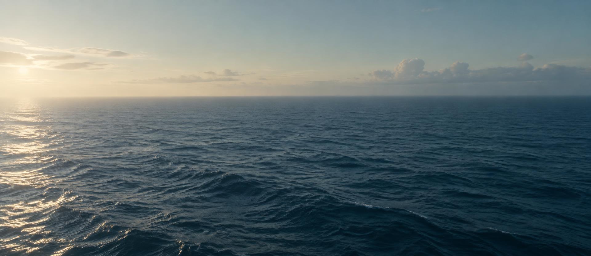 An empty open sea meeting a pale morning sky